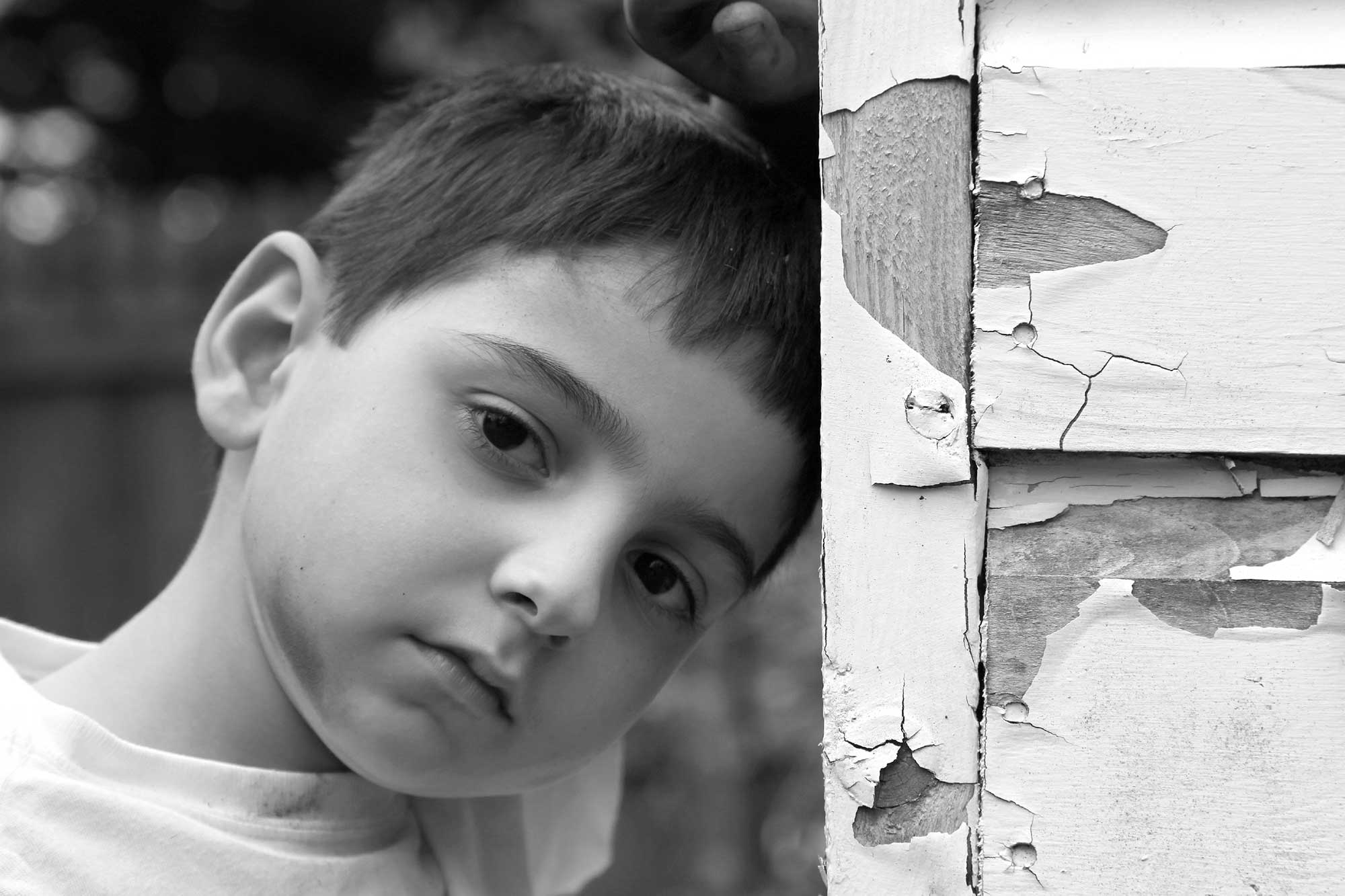 Boy leaning against wall with peeling paint