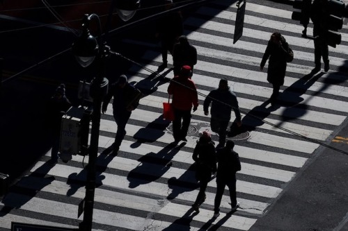Photo of shadowed people walking along city street