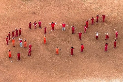 Detainees forming an SOS sign with their bodies to be seen from above
