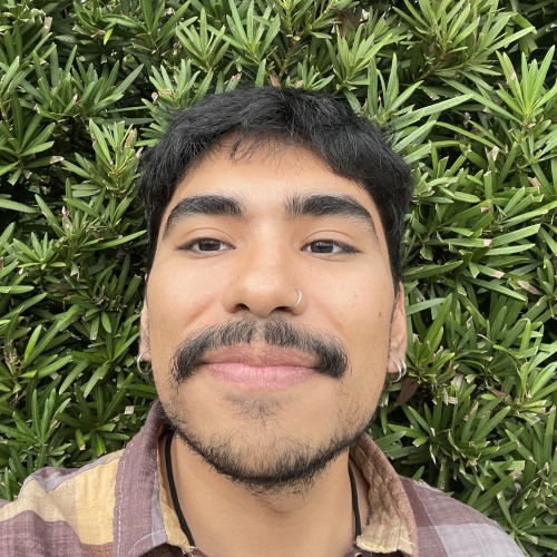 Jonathon Briones smiling in front of a leafy green background