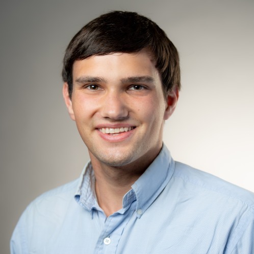 Adamson Bryant smiling in front of a gray background