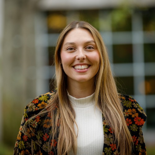 Chelsie Cintron smiling in a floral blazer outside a university building.