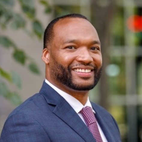 Enver Holder-Hayes smiling in an outdoor background.