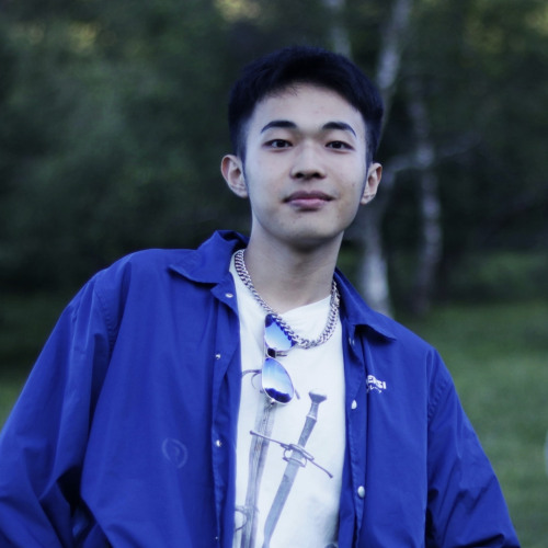 Zachk Huang smiling and posing in front of park greenery.