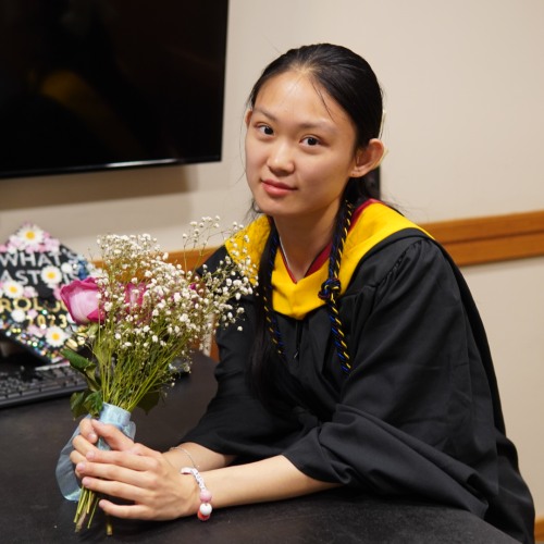 Yingyue Jiang holding flowers in a classroom.