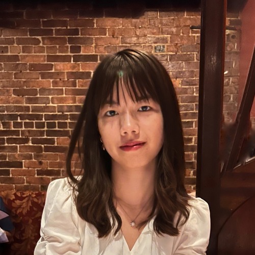 Yitong Liu sitting in front of an exposed brick background.