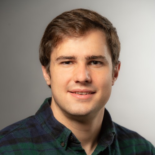 Sean McCulloch smiling in front of a gray background.