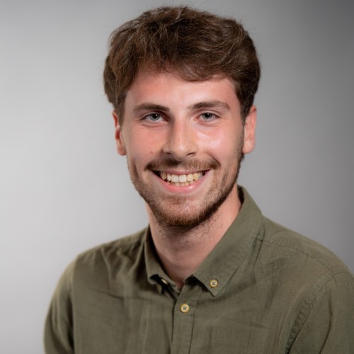 Luca Rizzotti smiling in front of a gray background