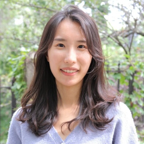 Photo of Jiwan Lee, Asian woman with long brown hair, wearing a purple shirt and standing against a greenery background