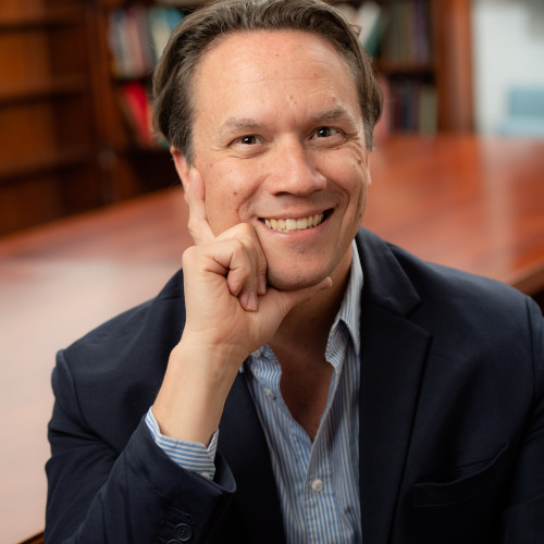 Photo of Lin Fisher who is a white male with short brown hair and is wearing a blue striped collared shirt with dark gray blazer