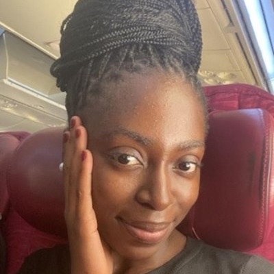 Stella Oyekanmi who has long black hair that is worn up and braided and she is wearing a dark green t-shirt