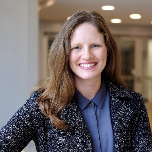 Alexandra Coooperstock wearing blue blouse and dark blue jacket against blurred university background