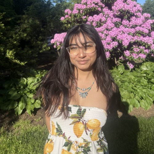 Karla Munoz wearing strapless flowered dress against an outdoor floral backdrop