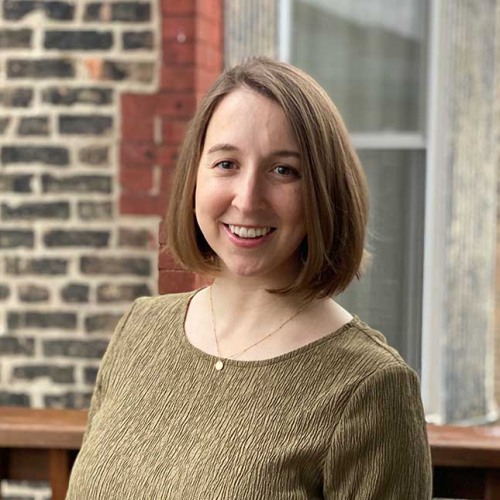Elly Field wearing green shirt against a brick building and window