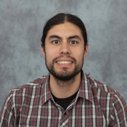 Carlos Alberto Tello Barreda wearing plaid shirt on gray background